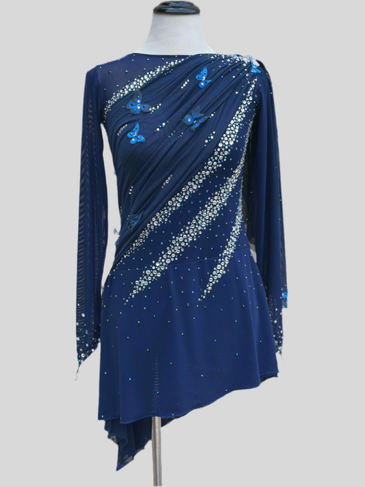 Elegant butterfly figure skating dress in deep blue with crystals, draped design, and open back – sparkle on ice.