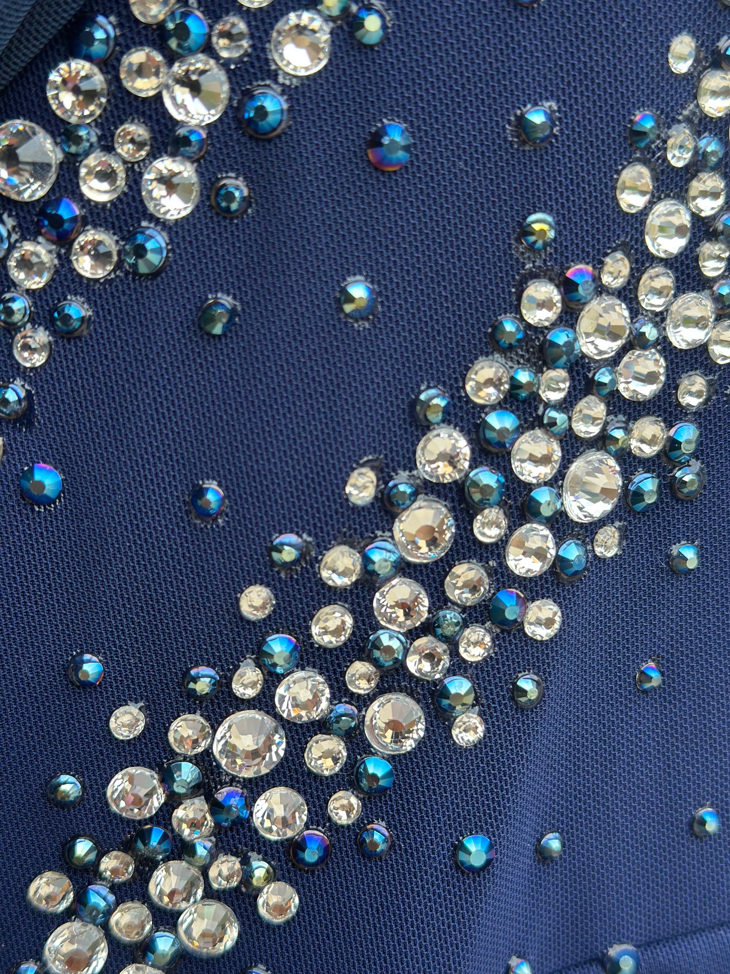Elegant butterfly figure skating dress in deep blue with crystals, draped design, and open back – sparkle on ice.